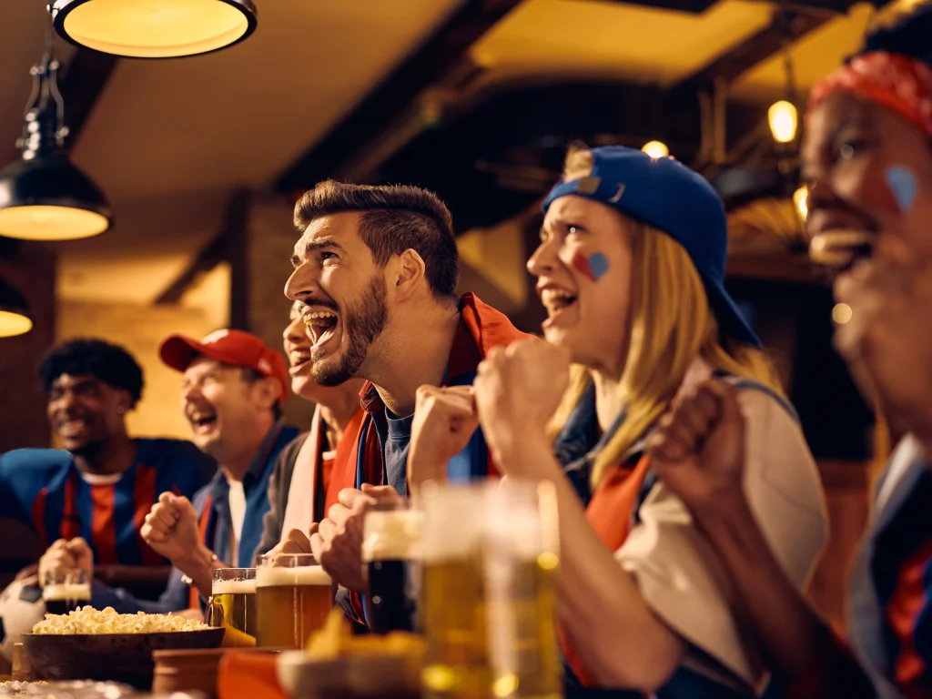 Fans cheering during World Cup 2026 while enjoying fast food, highlighting the effects of snacking and excitement on overall health.